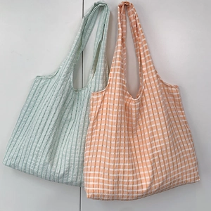 Detail of grid patterned canvas tote bags in light green and orange check patterns
