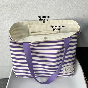 Detail of striped canvas tote showing magnetic closure and interior zipper pocket