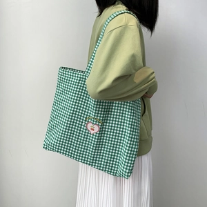 Détail de la broderie cerise et du motif à carreaux verts sur le sac en toile