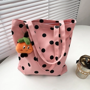 Pink polka dot canvas tote bag featuring an orange plush pumpkin keychain and top zipper