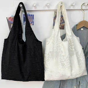 Minimalist textured tote bags with leaf patterns in black and white displayed on a wall