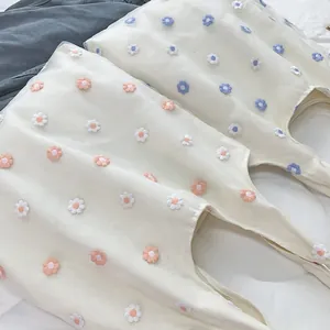Détail de la broderie florale sur un sac en toile beige avec des marguerites colorées