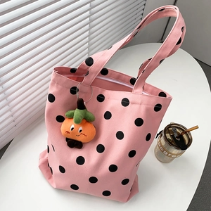 Close-up of pink canvas tote bag with black polka dots and orange plush charm