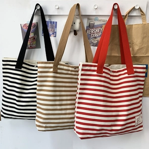 Detail of striped canvas tote bags with reinforced handles and metal snap closure