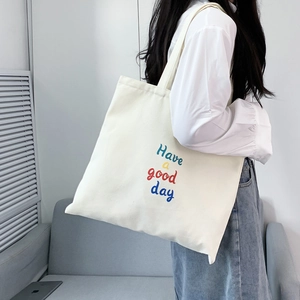 Detail of white canvas tote bag with Have a Good Day print shown on shoulder
