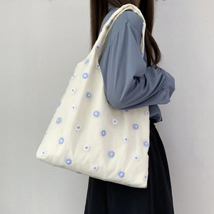 Détail du sac cabas en toile blanche avec broderies de fleurs 3D bleues sur l'épaule