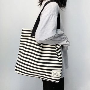 Close-up of black and white striped canvas tote bag with cute bear patch detail