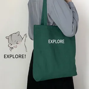 Large dark green canvas tote bag with chu qu lang print carried by a model outdoors