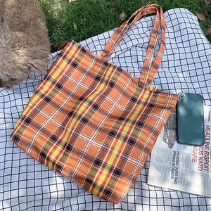 Scène de pique-nique montrant un grand sac fourre-tout en toile à carreaux orange