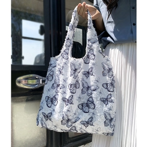 Detail of white canvas tote bag with butterfly prints and fuzzy textured fabric
