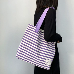 Detail of purple striped canvas tote bag featuring a cute white cartoon bear embroidery