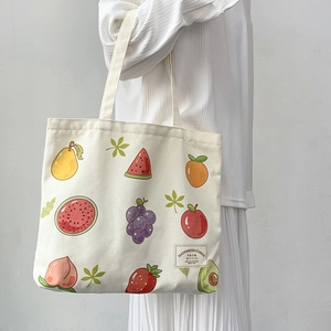 Detail of white canvas tote bag with vibrant fruit illustrations and woven quote label