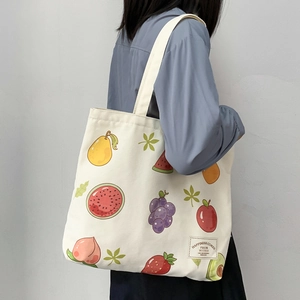 Detail of canvas tote bag featuring vibrant cartoon fruit prints and textile label