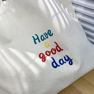 Minimalist canvas tote bag with colorful 'Have a good day' text in natural window light