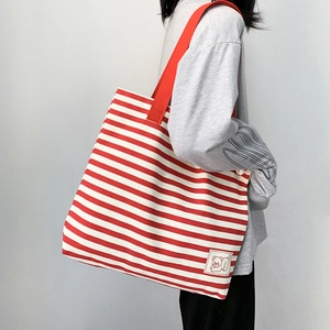 Close-up of a red and white striped canvas tote bag with a wide shoulder strap