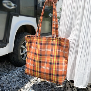 Photo en extérieur d'un sac cabas vintage à carreaux orange avec de longues poignées