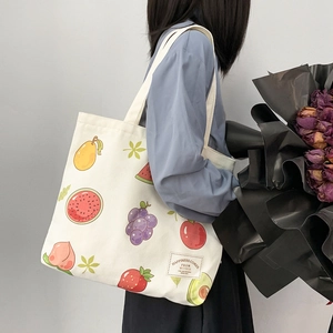 Detail of canvas tote bag showing colorful fruit illustrations and branded fabric label