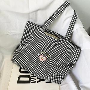 Détail d'un sac cabas en toile à carreaux noirs et blancs avec broderie cerise douce