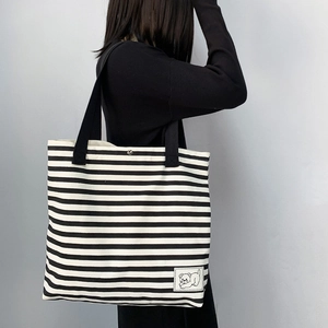 Detail of striped canvas tote bag showing silver magnetic snap closure and bear patch