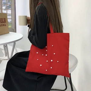 Detail of red tote bag with pearl decorations worn over the shoulder for daily commute
