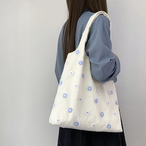 Gros plan détaillé du sac cabas blanc en toile avec broderies et fleurs en dentelle 3D bleues