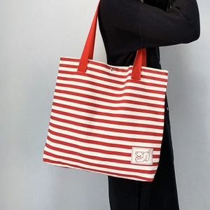Detail of red striped canvas tote with cute bear patch and secure magnetic closure