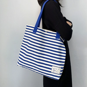 Detail of blue striped canvas tote bag showing the cartoon bear patch and soft texture