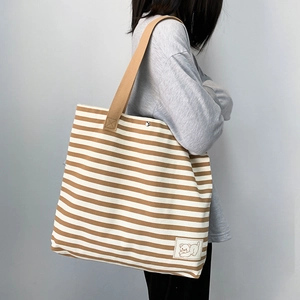 Detailed side view of large striped canvas tote bag with a cute bear patch