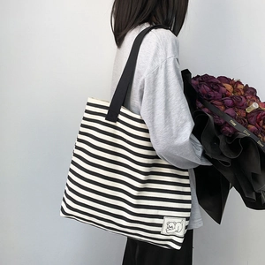 Close-up of large canvas shoulder bag featuring black and white stripes and bear patch