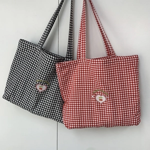 Détail des sacs en toile à carreaux rouges et noirs avec broderie cœur de cerise douce