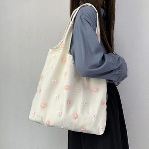 Détail de broderie de marguerites 3D sur un sac à bandoulière en toile crème d'été