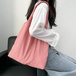 Borsa tote in tela a quadretti rossi e bianchi indossata da modella in studio minimal