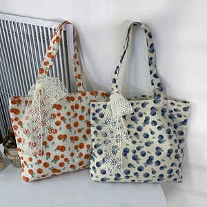Close-up of floral canvas tote bags featuring lace bows and fruit patterns