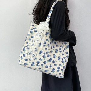 Floral canvas tote bag featuring blueberry print and large white lace bow shoulder strap