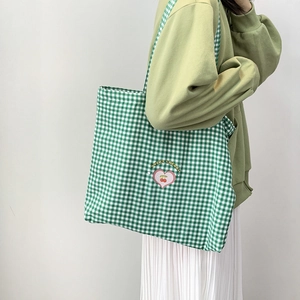 Détail d'un cabas en toile à carreaux verts avec imprimé cerise et motifs de cœur