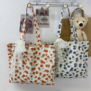 Detailed view of floral canvas tote bag featuring orange patterns and a lace bow charm