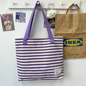 Detail of purple striped canvas tote with embroidered cat patch and magnetic metal snap