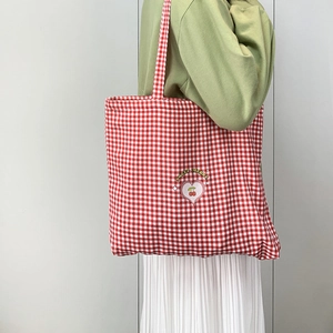 Détail du sac cabas en toile à carreaux rouges avec imprimé cœur cerise et bandoulière