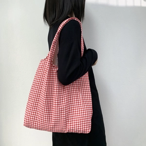 Grande borsa tote in tela a quadretti rossi e bianchi portata a spalla su un abito nero