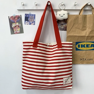 Detail of red striped canvas tote bag with bear patch and secure metal snap closure