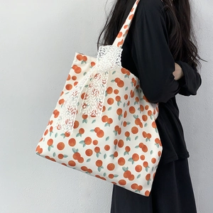 Detail of floral canvas tote bag featuring orange prints and white lace bow decoration