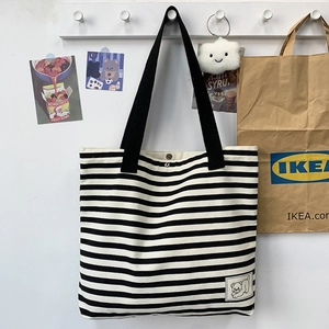 Detailed close-up of striped canvas tote bag showing reinforced straps and bear patch