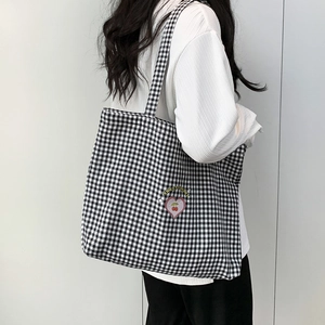 Détail d'un sac cabas en toile à carreaux avec écusson brodé en forme de cœur et cerises