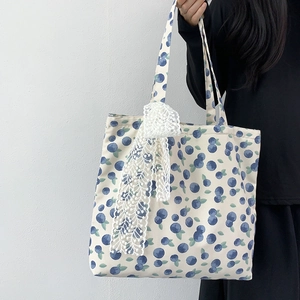 Close-up of canvas tote bag with blueberry print and decorative white lace bow detail