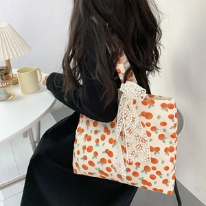 Detail of canvas tote bag showing lace bow decoration and vibrant orange fruit print