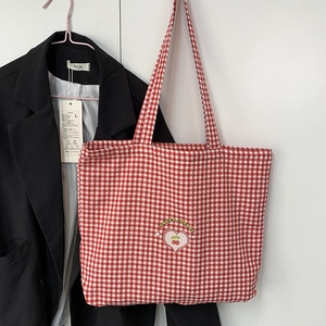 Détail du sac fourre-tout en toile à carreaux rouges et blancs avec broderie cerise