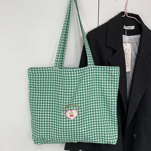 Détail du sac cabas en toile à carreaux verts et blancs avec broderie de cerises
