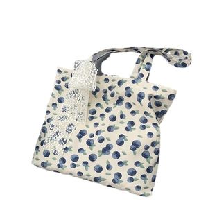 Floral canvas tote bag with blueberry print and lace bow decoration on white background