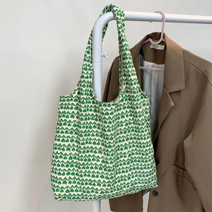 Detail of knit tote bag featuring green tulip floral pattern on beige fabric material