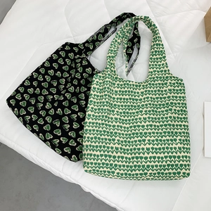 Detailed flat lay of knitted tulip and leaf pattern tote bags on white padding